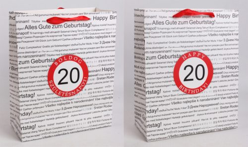 PAPÍRTASAK MATT, SZALAG FÜLLEL, FEHÉR ALAPON FEKETE, TÖBBFÉLE NEMZETKÖZI NYELVEN HAPPY BIRTHDAY FELIRATTAL A HÁTTÉRBEN, PIROS KARIKÁBAN ÉVSZÁMMAL, 20